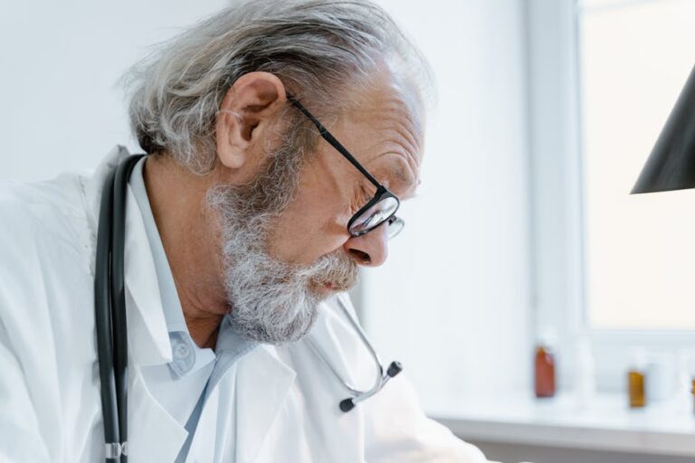 senior-doctor-with-glasses-and-stethoscope-focused-on-work-i
