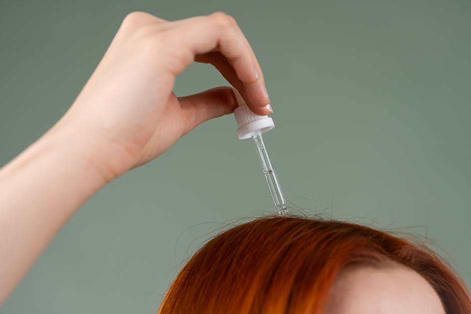 close-up-of-hand-applying-hair-serum-on-red-hair-with-a-drop